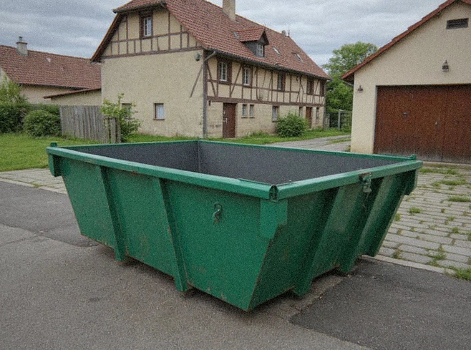 Benne verte vide livrée dans la cour d'une maison alsacienne à colombages, location de benne MOL Bennes à Molsheim